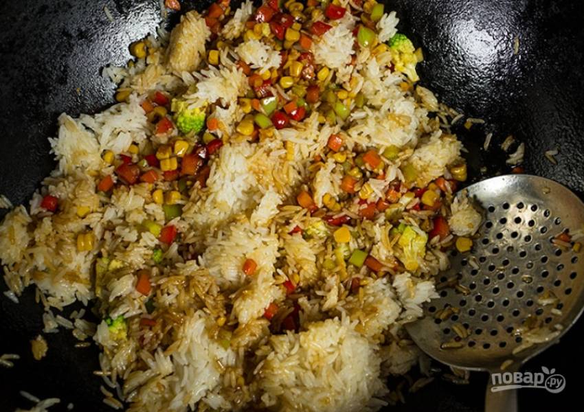 Аккуратными движениями перемешайте рис с овощами. Доведите блюдо до готовности и снимите с огня.
