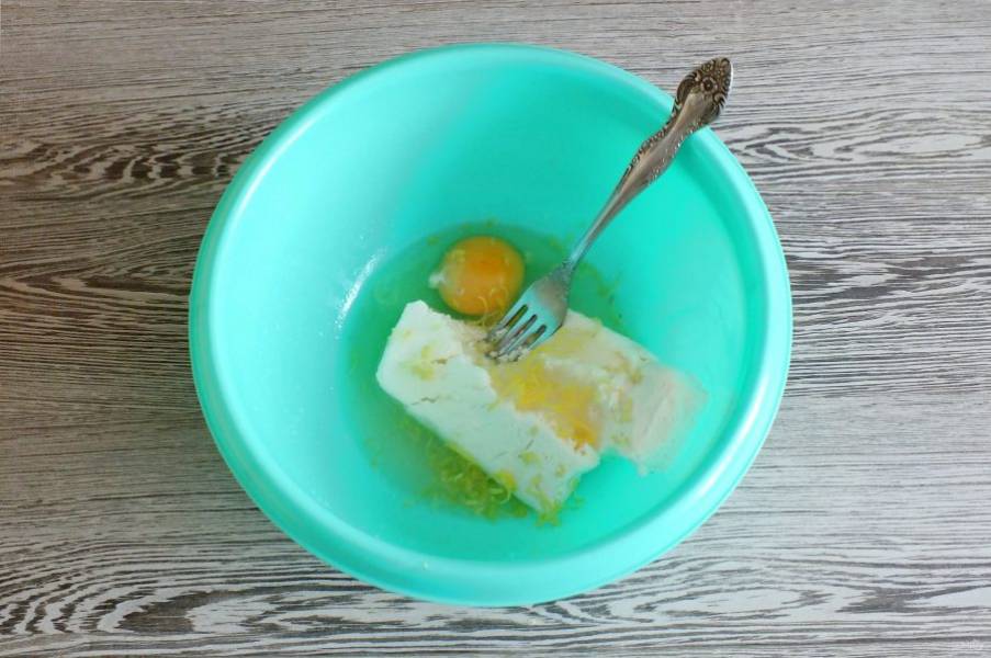 Соедините в чаше творог, яйца, сахар, цедру и сок половинки лимона. Перемешайте вилкой.