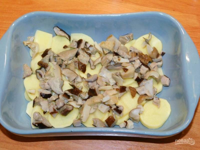 В форму для запекания выложите картофель, нарезанный кружками и грибы.
