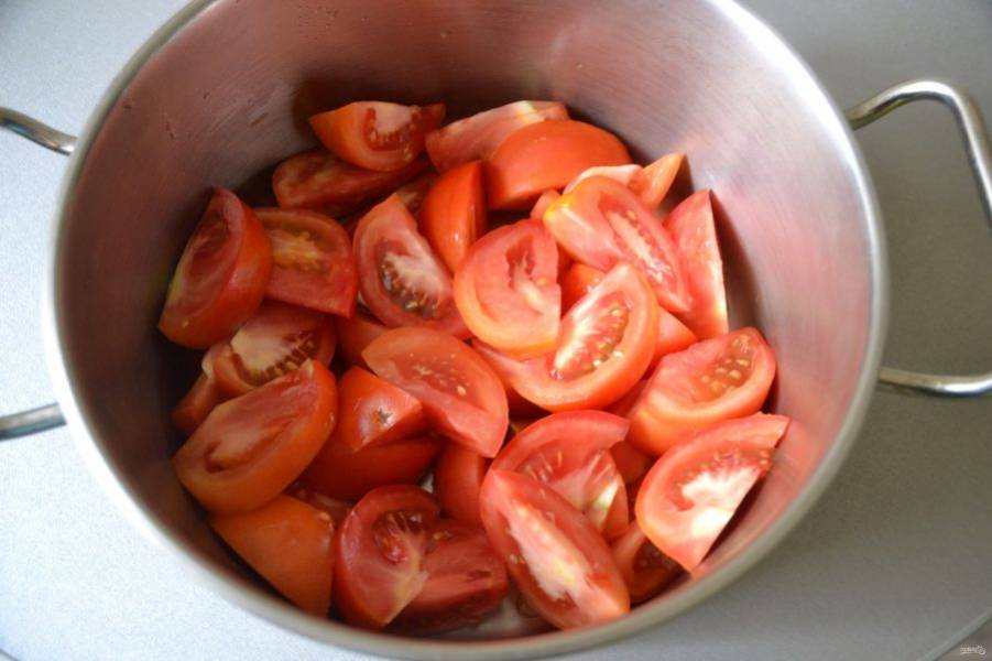 В кастрюлю с толстым дном выложите нарезанные дольками помидоры.