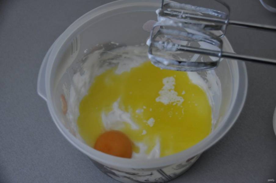 Добавьте яичный желток и растопленное сливочное масло, масло не должно быть слишком горячим, еще раз взбейте миксером.