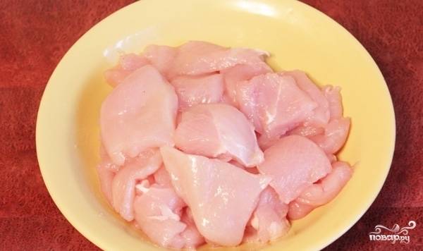 Теперь нарезаем куриное филе на кусочки со стороной около 3 сантиметров, затем солим их и посыпаем молотым перцем.