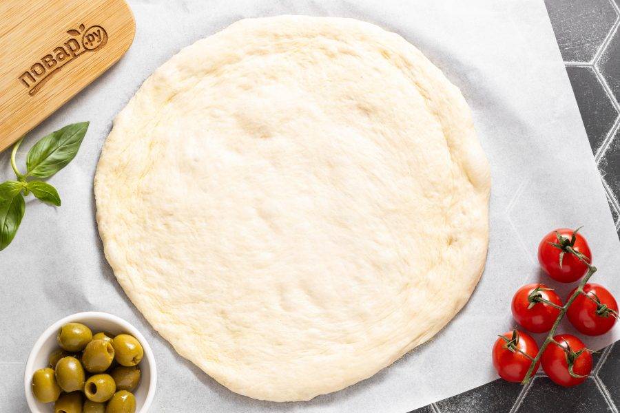 Выложите тесто на поверхность присыпанную манкой и аккуратно растяните. Придайте ему форму круга или овала, сформируйте бортики.