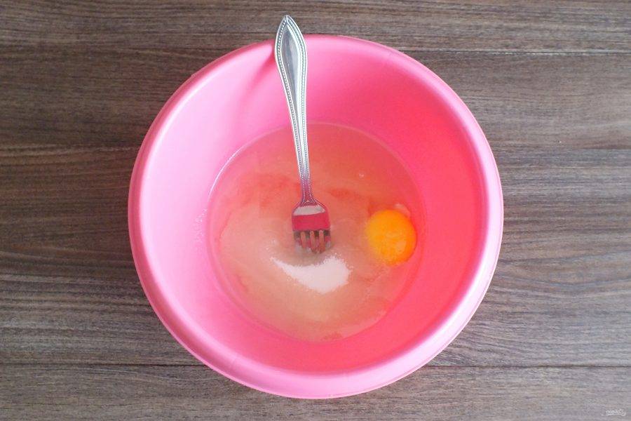 В чаше соедините растительное масло, одно яйцо, белок и сахар. Перемешайте вилкой. Желток отложите для смазки рулета.