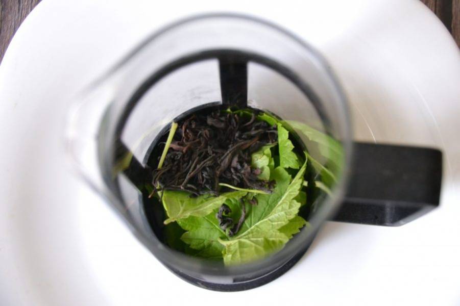 Положите смородиновые листья в чайник для заварки или в френч-пресс, всыпьте черный чай, залейте кипятком.
