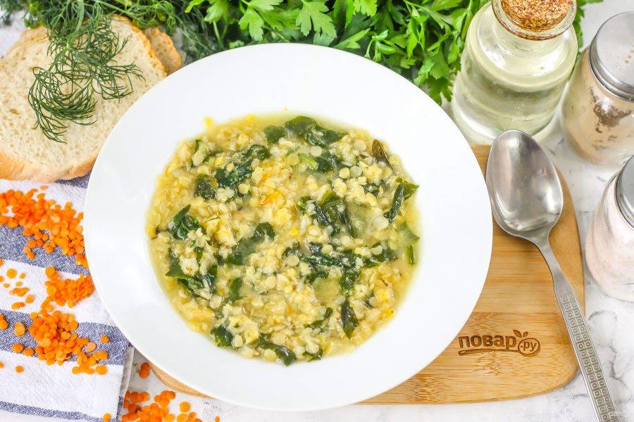 Разлейте горячий суп из чечевицы со шпинатом в тарелки, подайте к столу с сухариками.