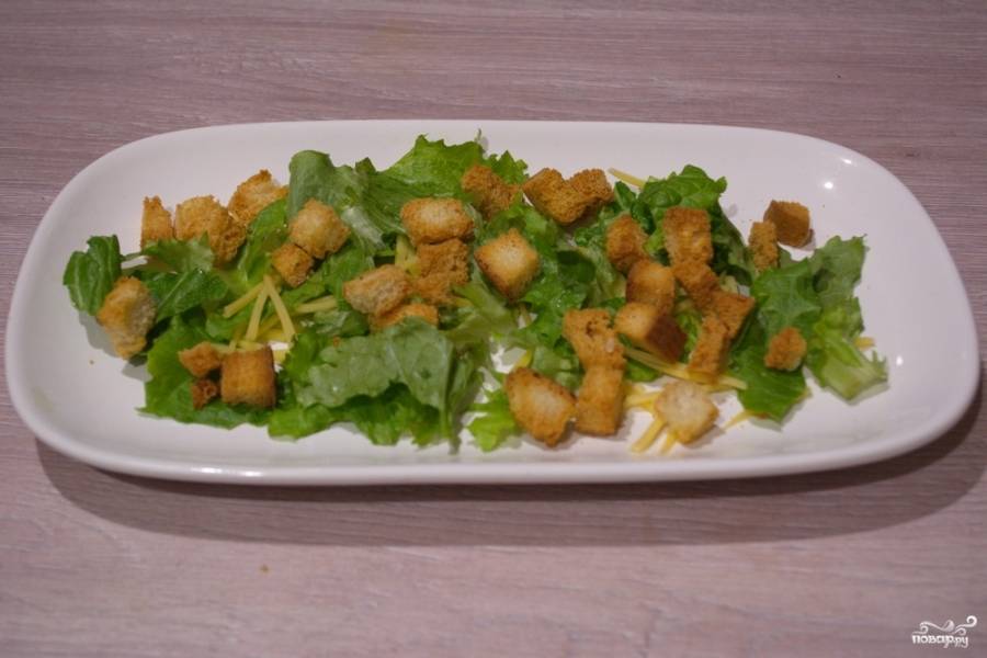В духовке подрумяньте сухарики. Остывшие сухарики выложите на листья салата. Горячими сухарики не выкладывайте, т.к. они испортят внешний вид салата.