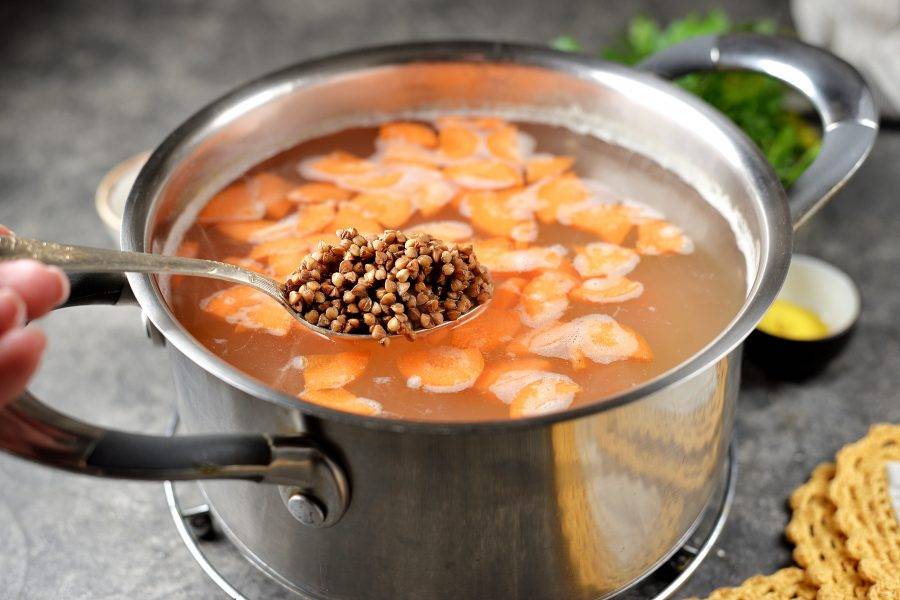 Переложите овощи в кастрюлю, сразу же добавьте промытую гречку. Варите суп минут 15. 