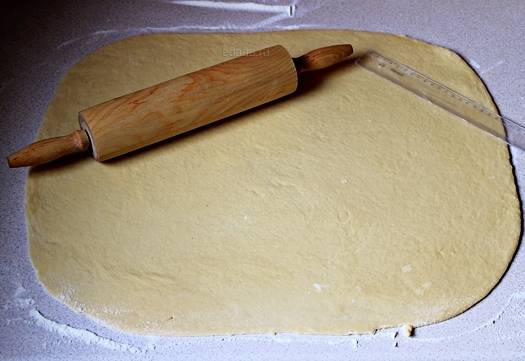 Присыпьте стол мукой, раскатайте тесто в широкий пласт. Смажьте его растопленным сливочным маслом.
