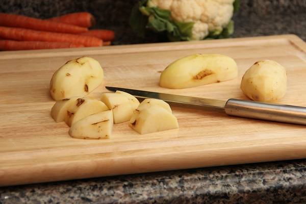 2. Вымыть и очистить картофель. Нарезать небольшими кубиками. При желании можно в рецепт приготовления запеканки из цветной капусты и картофеля использовать и другие овощи - морковь, кабачок, например. 