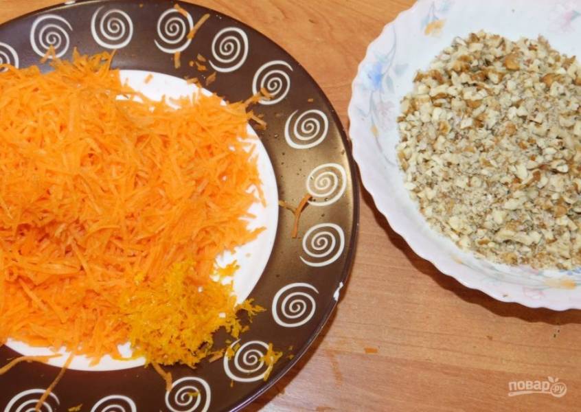 Для приготовления бисквита натрите морковь на мелкой терке. Снимите цедру с апельсина и порубите орехи ножом.