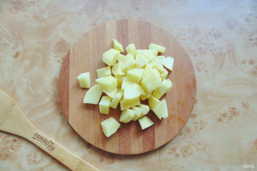 Очистите картофель, вымойте и нарежьте кубиками. Добавьте в кастрюлю и продолжайте варить суп почти до готовности.