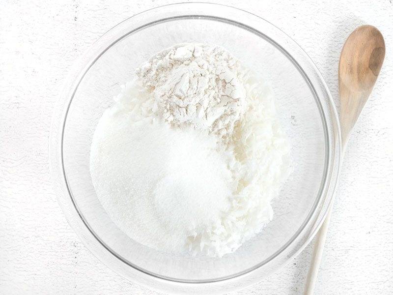 1.	Выложите в миску кокосовую стружку и добавьте к ней муку, сахар, соль, перемешайте.