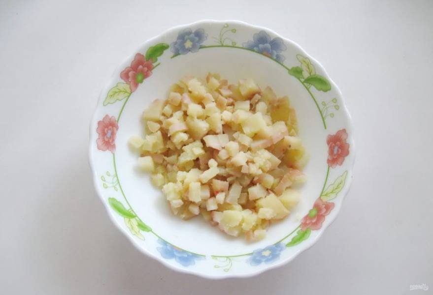 Картофель сварите в "мундире", охладите, очистите и нарежьте мелкими кубиками. Выложите в салатник.