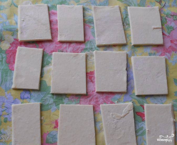 Слоеное тесто разморозьте, разверните и нарежьте небольшими квадратами. 