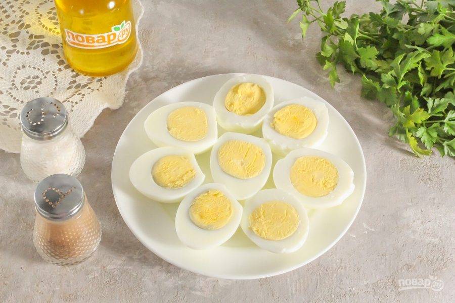 Отварные куриные яйца аккуратно очистите от кожуры и промойте в воде. Разрежьте вертикально пополам и выложите лодочки из яиц на тарелку.