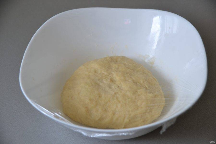Всыпьте муку с дрожжами в молочно-масляную смесь, замесите тесто, накройте пленкой, поставьте в теплое место для брожения на 1 час. 