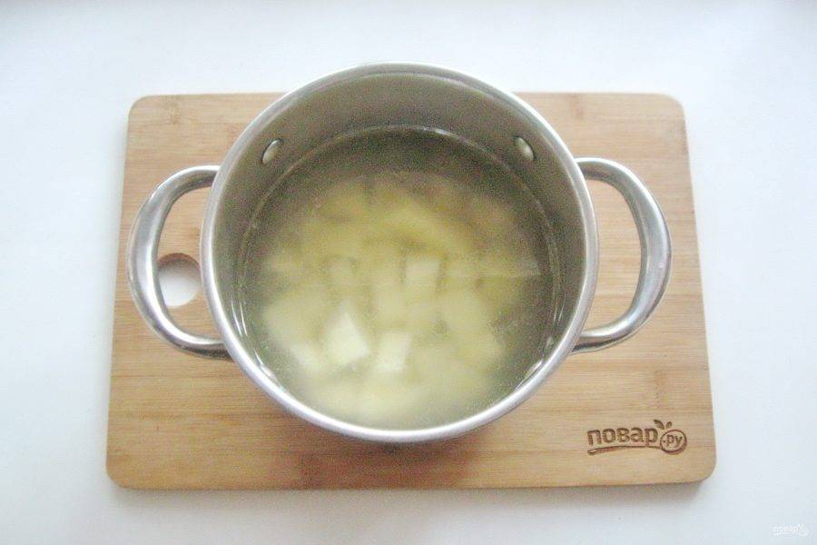 В кастрюлю налейте куриный бульон. Картофель очистите, помойте и нарежьте кубиками. Добавьте в кастрюлю с бульоном.