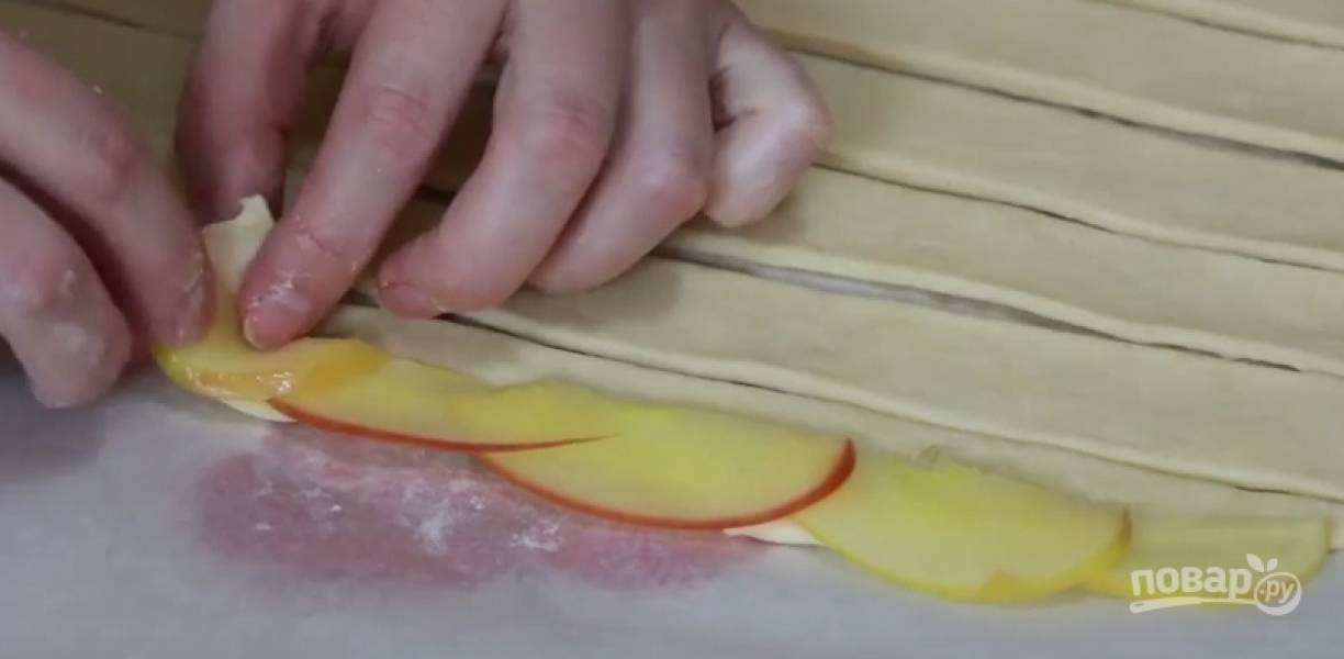 Тесто разморозьте и порежьте на небольшие полосочки, выкладывайте яблоки внахлест. Сворачивайте каждую полосочку, формируя розу.