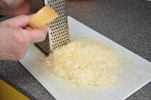 2. Натираем сыр на мелкой терке в отдельную посуду. В другой емкости разбиваем куриные яйца, солим и приправляем их, после чего хорошенько разбалтываем вилкой.
