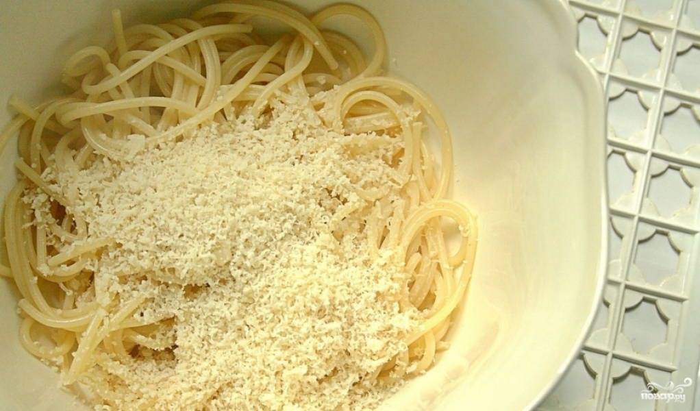 Добавьте в варёные спагетти оливковое масло и перемешайте. Посыпьте тёртым сыром Пармезан.