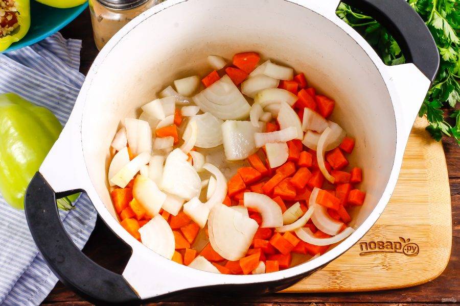 Очистите от кожуры лук и морковь, нарежьте крупными кубиками, предварительно промыв. Прогрейте в казане растительное масло и обжарьте в нем овощные нарезки примерно 3-5 минут до мягкости.