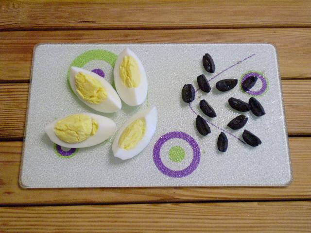 2. Яйцо режем на дольки. Маслины на 4 части каждую.