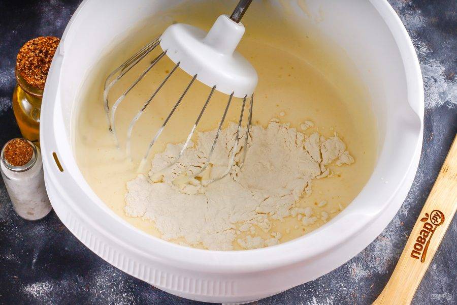 Куриные яйца взбейте с солью и 1 ст. сахарного песка в пышную пену примерно 3-5 минут. Затем вмешайте аккуратно пшеничную муку, замешивая бисквитное тесто. Разогрейте духовку до 180 градусов.