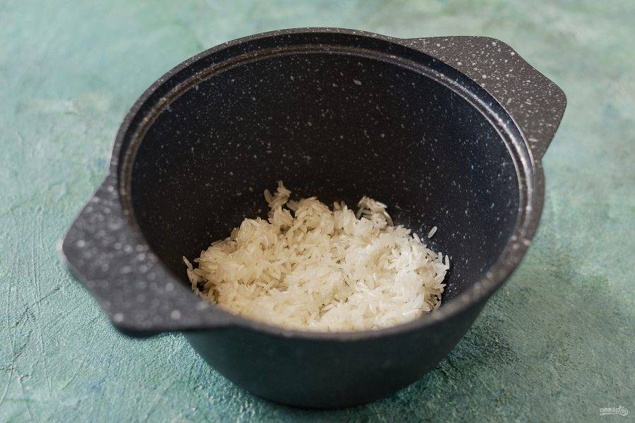 Обжарьте в кастрюле рис в небольшом количестве масла несколько минут.