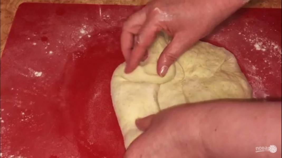 Разделите тесто на 2 части, каждую часть округлите. Накройте тесто влажным полотенцем и оставьте на 10 минут. Сформируйте хлеб овальной формы, аккуратно разомните тесто в небольшую лепешку, сложите треть теста на себя. 