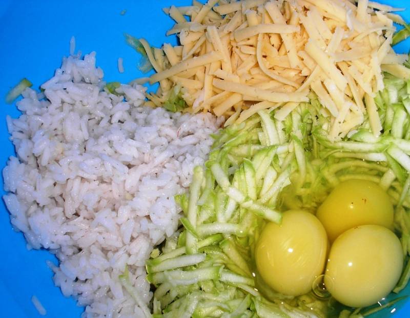Кабачок потрите и смешайте с рисом, луком, яйцами и половиной тертого сыра. Добавьте соль и специи по вкусу. 