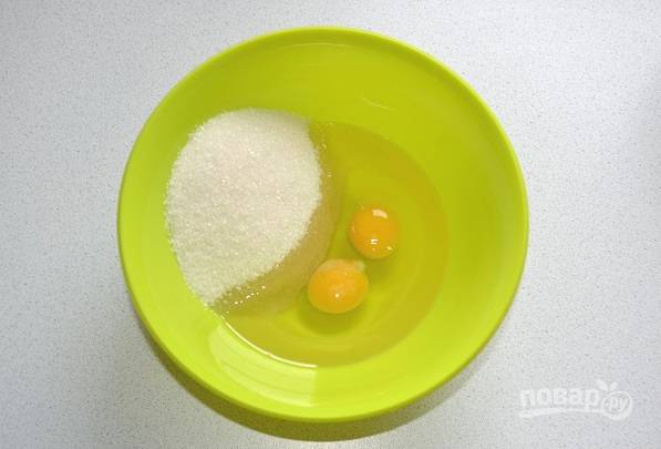 В глубокую миску вбейте яйца и всыпьте сахар. Взбейте венчиком до однородности. Влейте растительное масло и еще раз перемешайте. 