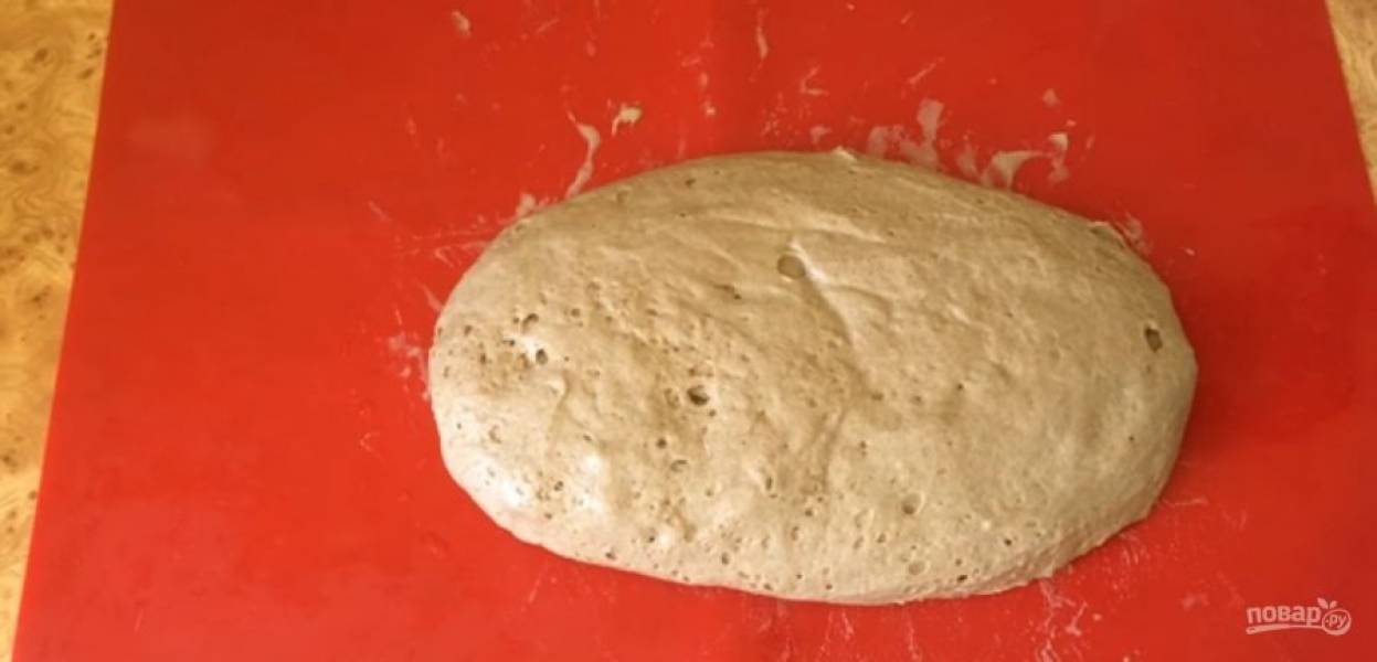 3.  Выложите тесто на влажную рабочую поверхность и сгладьте поверхность. Выложите тесто в форму для выпечки, смазанную маслом. Влажными руками хорошо утрамбуйте тесто и несколько раз ударьте формой о стол. 