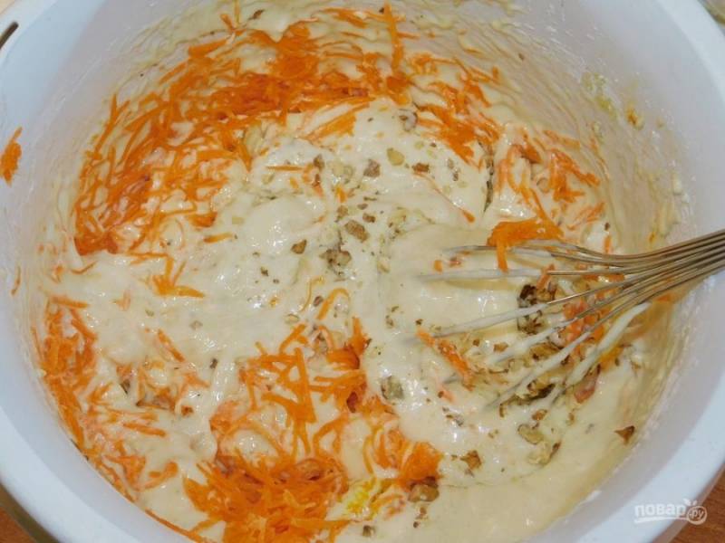 Затем добавьте в тесто морковь, натертую на средней терке и порубленные орехи. Вмешайте все равномерно в тесто.