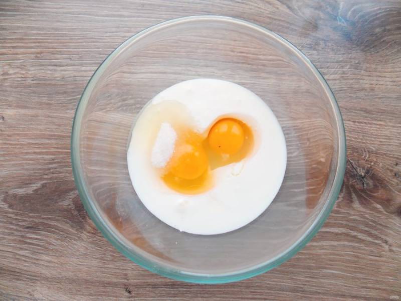 Налейте в миску кефир и разбейте яйца. Всыпьте соль и сахар, все перемешайте до однородной массы.
