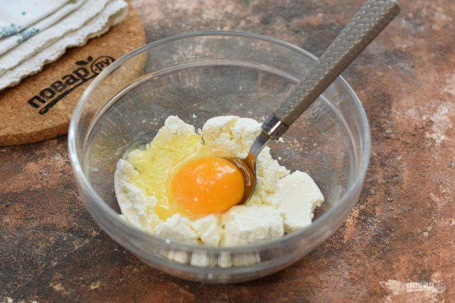 В глубокую миску переложите творог, добавьте куриное яйцо, щепотку соли и при желании заменитель сахара.