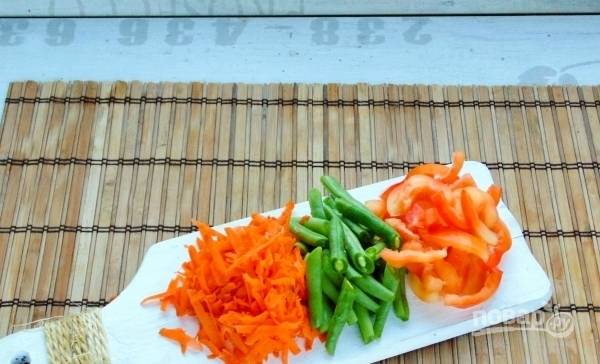 Вымойте стручковую фасоль, болгарский перец, морковь. У перца достаньте сердцевинку с семечками, морковь очистите и натрите на крупной терке. Перец порежьте соломкой. 