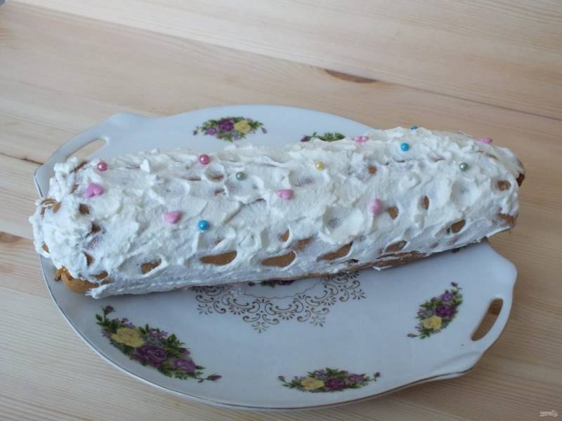 Закрутите рулет, смажьте сверху сливками, украсьте по желанию.