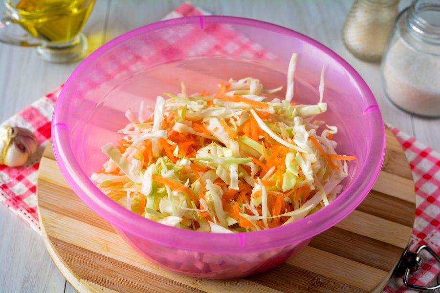 Перемешайте капусту с морковкой, слегка прижимая овощи чистыми руками. Так капуста быстрее пустит сок и обмякнет.