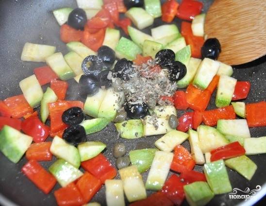 Разогрейте на плите сковороду. Влейте на нее немного оливкового масла и выложите овощи кубиками. Обжаривайте на сильном огне пять минуток. Затем бросьте к овощам нарезанные пополам маслины и посыпьте все орегано. 