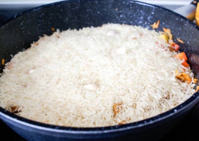 Засыпаем сверху рис, не перемешивая его. Втыкаем в рис зубчики чеснока.