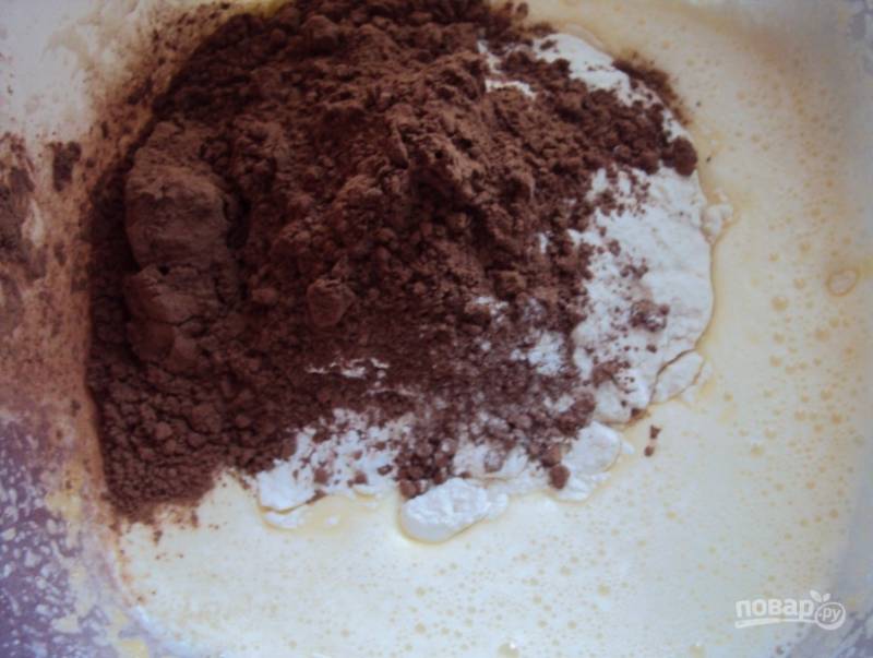 2. Просеянную муку и какао добавьте к желтковой массе, продолжайте взбивать.