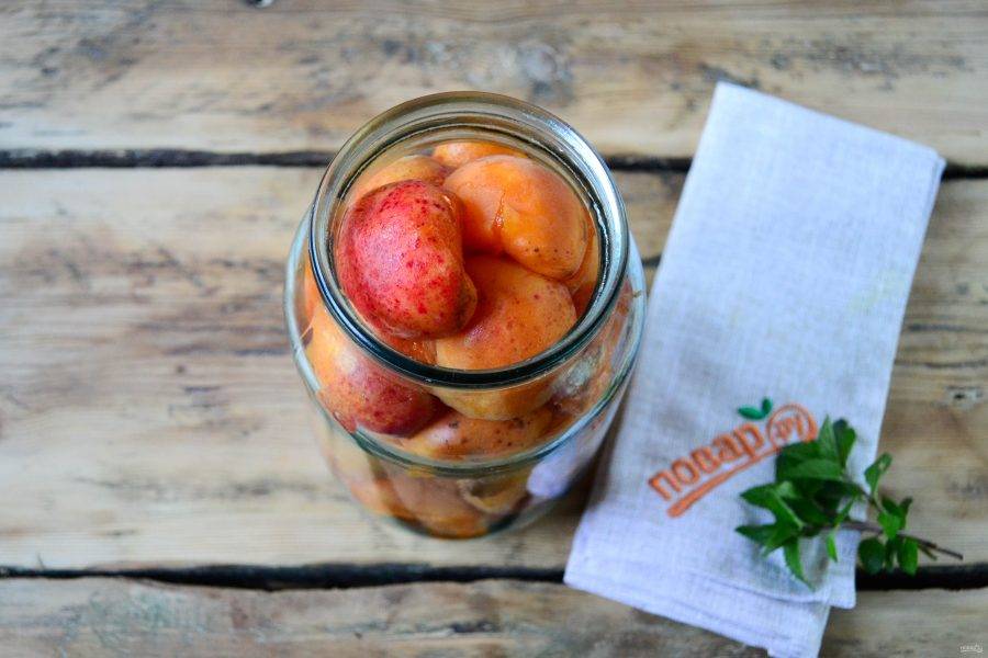 В чистую стерильную банку сложите половинки абрикосов. Слишком плотно не укладывайте, чтобы не помять фрукты и максимально сохранить их целостность.