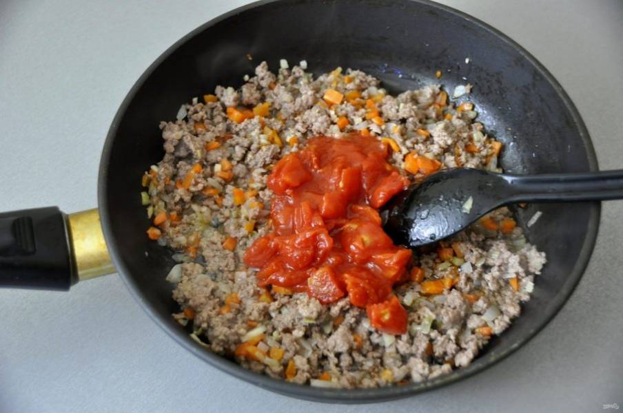 После того, как фарш обжарится, выложите томатную пассату или томатную польпу (помидоры в собственном соку с соусом), накройте крышкой и прожарьте до готовности.