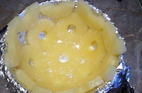 Форму для торта застелите фольгой, выложите кольцо ананасов в центр, по краям выложите остальные ананасы.