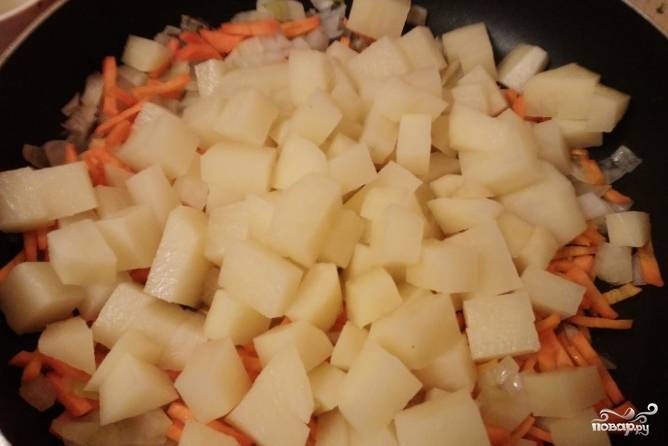 3.	Очистите картофель от кожуры. Нарежьте небольшими кусочками. Добавьте картофель к овощам на сковороде. Поставьте овощи на средний огонь. Готовьте под крышкой. Периодически овощи перемешивайте.