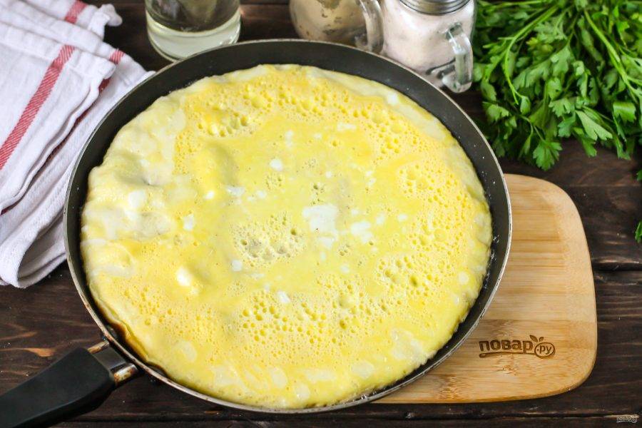 Прогрейте сковороду с растительным маслом, вылейте на нее яичную массу и убавьте нагрев. Обжарьте омлет до плотности в течение 2-3 минут, желательно накрыв сковороду крышкой.