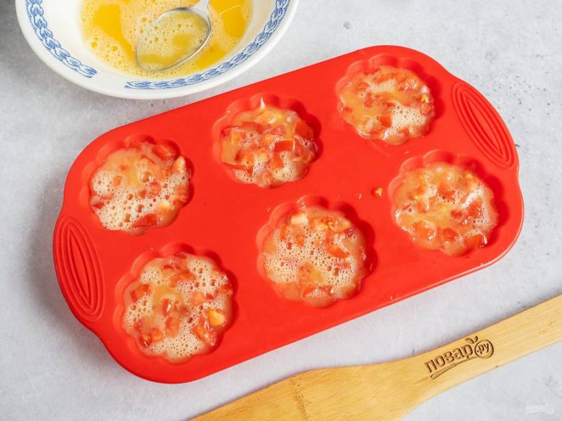 Затем выложите слой нарезанных мелким кубиком помидоров. Яйца взбейте вилкой с солью и полейте сверху на помидоры.