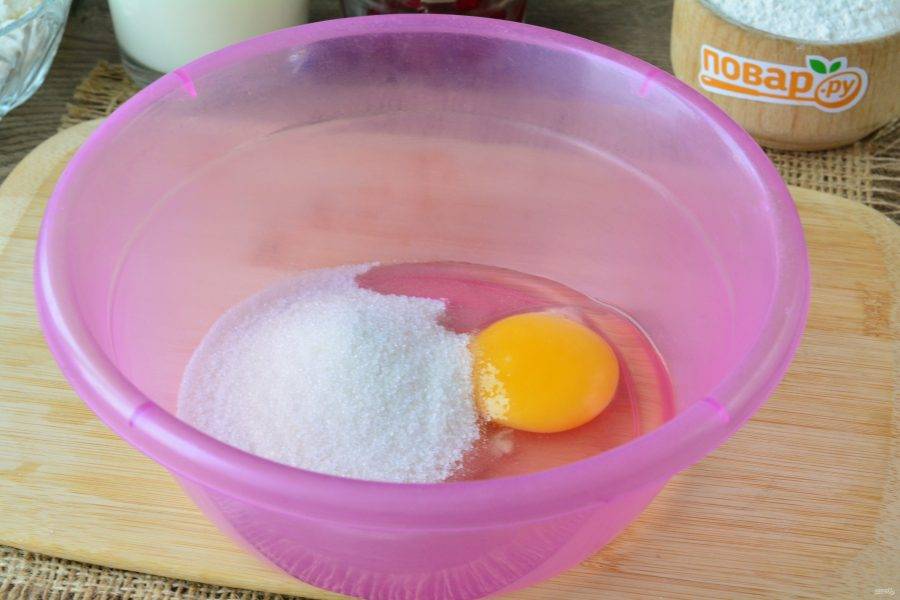Всыпьте в миску сахар (50 грамм). Вбейте куриное яйцо.
