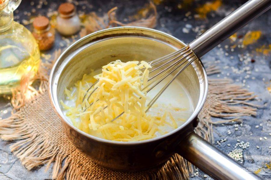 Сыр натрите на средней терке. Стружку сыра переложите в соус, немного сыра оставьте в стороне.